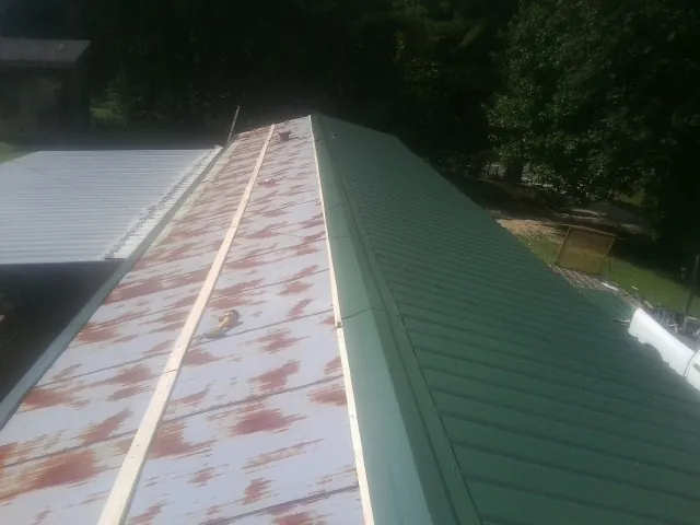 Old rusted panels beside newly installed green metal roofing — Wind Damage Roof Repair by Roofing Brothers in Oceanside