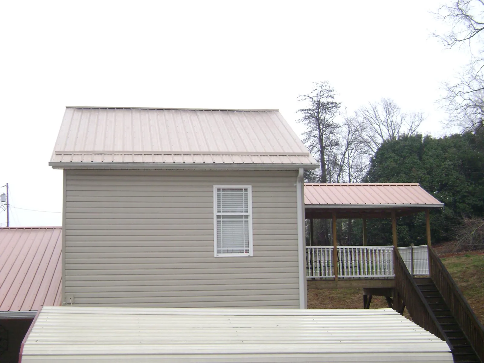Tan metal roofs on a two story addition and attached porch, from a Roof Replacement job in Oceanside